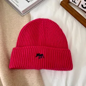 Detalle de gorro de punto rosa fucsia con textura acanalada y bordado de cebra