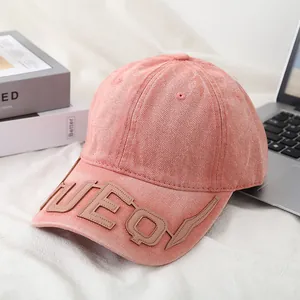 Detail of embossed UEQY letters on washed pink cotton denim baseball cap brim
