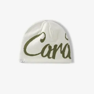 Cream knit beanie featuring green jacquard lettering and warm ear protection style