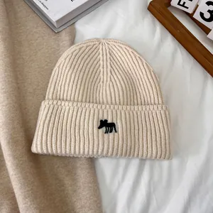 Primer plano de un gorro de punto beige con bordado de alce y textura de punto acanalado