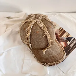 Detail of distressed vintage brown denim baseball cap featuring frayed edges and torn fringes