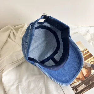 Detail view of denim military cap showing navy sweatband and adjustable metal buckle back