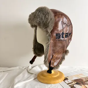 Détail de la toque aviateur en cuir marron avec doublure en fausse fourrure grise et étoile