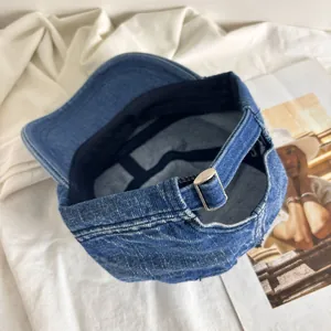 Close-up of blue washed denim baseball cap with adjustable metal buckle and strap