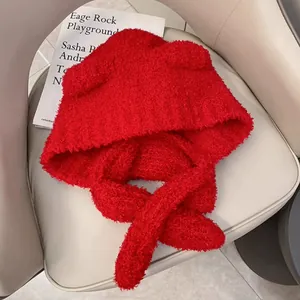 Detail van rode pluche muts met oorflappen en sjaal in zachte teddyfleece