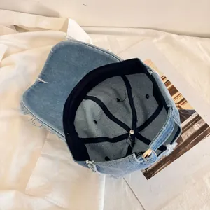 Detail view of distressed blue denim baseball cap showing frayed edges and inner lining