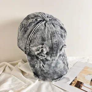Dettaglio del cappello da baseball in denim lavato vintage con strappi e trame logore