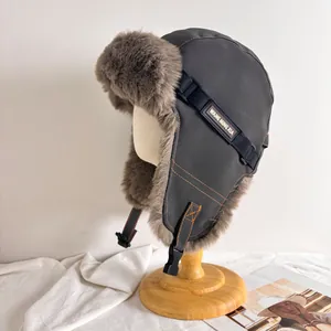 Detailaufnahme der winddichten Fliegermütze mit orangefarbenen Nähten und braunem Kunstpelz