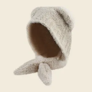 Detail van beige pluche beer oor kap met sjaal voor winterwarmte en zachte textuur