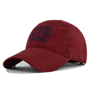 Close-up of distressed baseball cap in burgundy with navy embroidered lettering