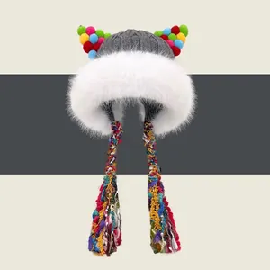 Dettaglio del cappello in maglia grigia con pompon colorati e bordo in ecopelliccia bianca