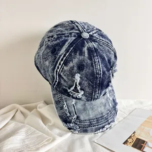 Dettaglio del cappello da baseball in denim lavato con acido blu scuro e bordi sfilacciati