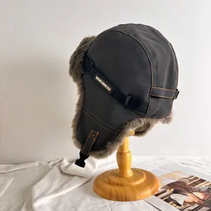 Detail der warmen Wintermütze mit dickem Kunstfellfutter und orangefarbenen Kontrastnähten
