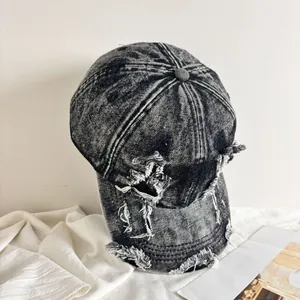 Dettaglio del cappello da baseball in denim lavato con bordi sfilacciati e stile usurato