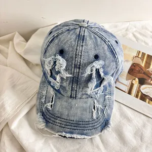 Dettaglio macro del cappellino da baseball in denim lavato con bordi sfilacciati e fori vintage