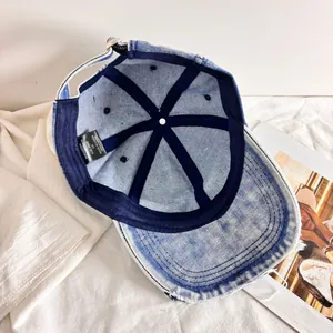 Dettaglio interno del cappellino in denim lavato con etichetta e fibbia in metallo