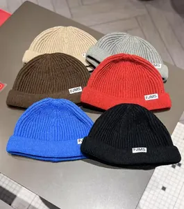 Flat lay of ribbed knit docker hats in six colors with woven FJMS side labels