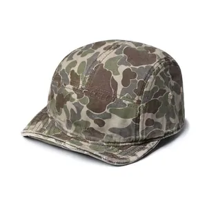 Detailed view of the camouflage 5-panel cap featuring a short soft brim and metal eyelets