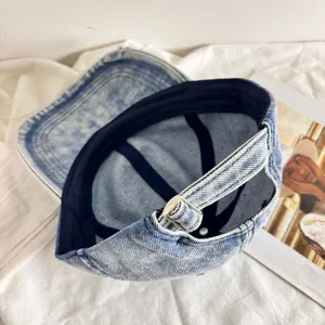 Dettaglio cappellino in denim lavato con bordi sfilacciati e fibbia in metallo regolabile