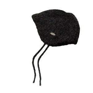 Premium wool knit bonnet with chin ties and metal logo detail for winter warmth