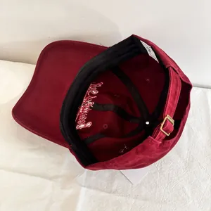 Detailed interior of a burgundy cotton baseball cap featuring metal buckle and sweatband