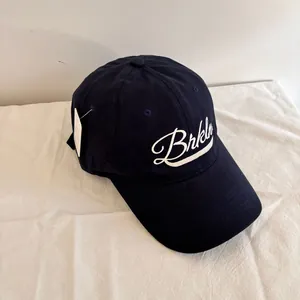 Detailed view of navy blue baseball cap with white Brkln embroidery and product tag