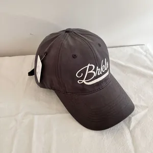Detail of dark grey baseball cap featuring white Brkln embroidery on cotton fabric