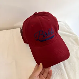 Macro detail of red cotton baseball cap featuring blue Brkln letter embroidery art