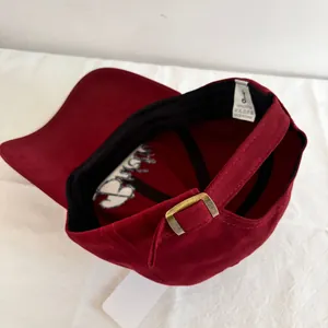Detail of red cotton baseball cap featuring adjustable bronze buckle and internal sweatband