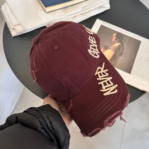 Detalle de gorra de béisbol granate con bordes desgastados y bordado Never Give Up