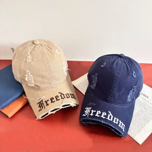 Dettaglio dei cappellini da baseball in stile distressed con ricamo Freedom e bordi logori