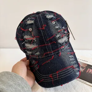 Close-up of distressed vintage denim baseball cap with red embroidery and frayed details