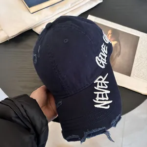 Detalle de gorra de algodón azul marino con bordado NEVER GIVE UP y acabado desgastado