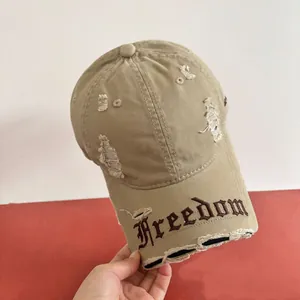 Dettaglio del ricamo gotico Freedom e dei fori consumati sul cappellino da baseball kaki