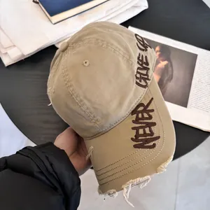 Primer plano de gorra de béisbol caqui con bordado Never Give Up y detalles de rotos usados