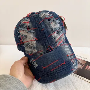 Close-up of vintage distressed blue denim baseball cap with red contrast stitching details