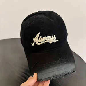 Close-up detail of white Always embroidery on distressed black cotton baseball cap