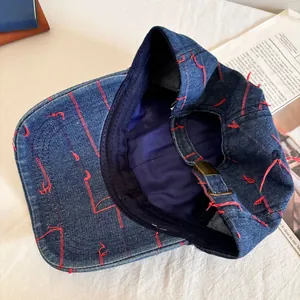 Detailed macro view of denim baseball cap with red contrast stitching and metal buckle