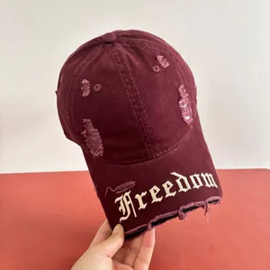 Dettaglio del cappellino da baseball bordeaux in cotone con strappi e ricamo Freedom