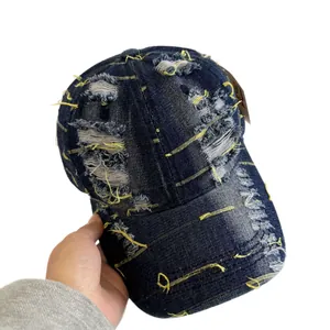 Vintage washed navy blue denim baseball cap with distressed rips and yellow stitching