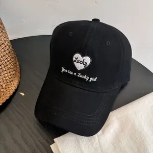 Detalle del bordado blanco Lucky Girl y el patrón de corazón en una gorra de algodón negro