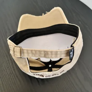 Detailed view of distressed khaki baseball cap featuring embroidered back lettering