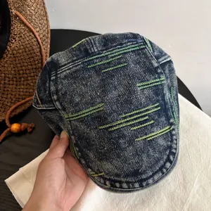 Detail of washed denim flat cap showing blue fabric and colorful contrast stitching