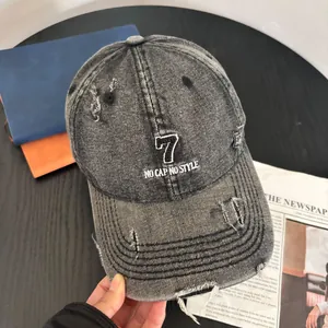 Detail of distressed grey denim baseball cap with white number 7 and slogan embroidery
