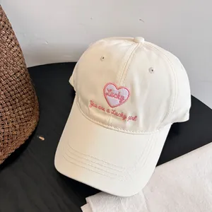 Detalle de gorra de béisbol de algodón blanco con parche de corazón y bordado Lucky