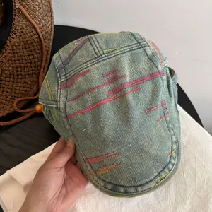 Detail of colorful embroidery and washed denim texture on a light blue beret cap