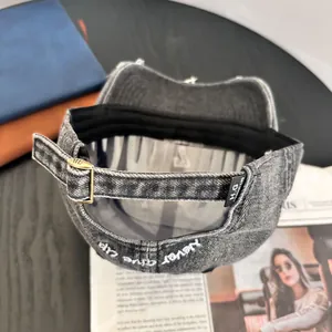 Detail of adjustable metal buckle and 'Never Give Up' embroidery on washed denim cap