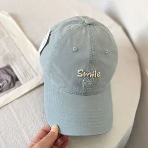 Detail of blue cotton baseball cap with Smile embroidery and heart smiley icon