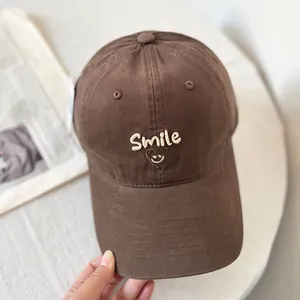Detail view of the smile embroidery and fine stitching on the brown cotton baseball cap