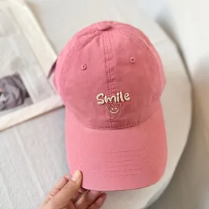 Close-up of Smile lettering and heart emoji embroidery on pink cotton baseball cap